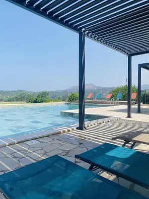 a swimming pool with blue water and a metal roof at Résidence Ellada 3 Appartement 12 in Cargèse