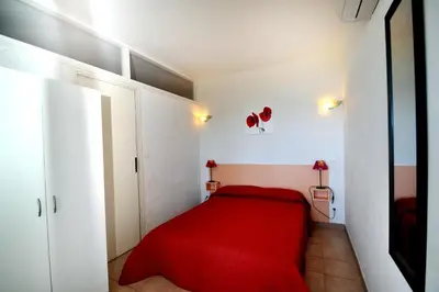 a bedroom with a red bed in a white room at Résidence Ellada 3 Appartement 12 in Cargèse