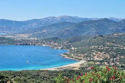 a sandy beach with an umbrella and the ocean at Studio with sea view in Calcatoggio