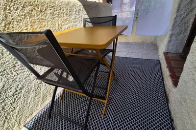 a yellow table and chairs sitting next to a wall at Studio with sea view in Calcatoggio