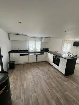 a large kitchen with white cabinets and a wooden floor at Appartement proche de la rivière et de la plage ! in Vico