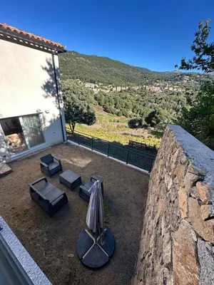 a patio with an umbrella and chairs and a table at Appartement proche de la rivière et de la plage ! in Vico
