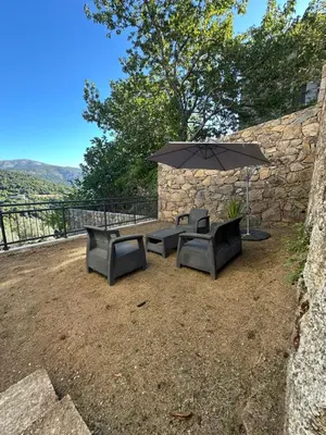 a patio with two benches and an umbrella at Appartement proche de la rivière et de la plage ! in Vico