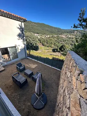 a patio with an umbrella and chairs and a table at Appartement proche de la rivière et de la plage ! in Vico