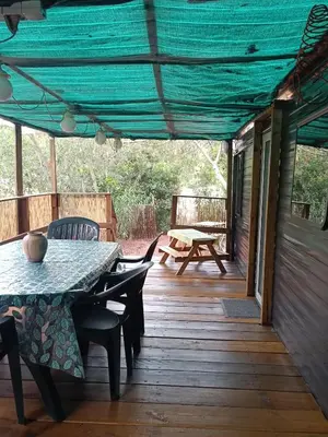 a patio with a table and chairs on a deck at Chalet et Mobile Home, au sein du maquis Corse avec piscine PRIVATIVE 9mx4m in Zonza