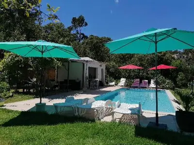 a swimming pool with umbrellas and chairs and a pool at Chalet et Mobile Home, au sein du maquis Corse avec piscine PRIVATIVE 9mx4m in Zonza