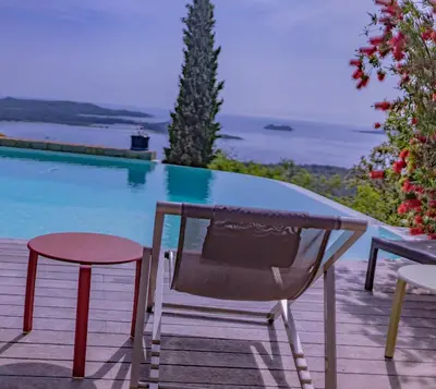 a chair and table next to a swimming pool at Villa Panorama Porto-Vecchio in Porto-Vecchio