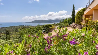 a view of a house with flowers in the foreground at Villa Panorama Porto-Vecchio in Porto-Vecchio