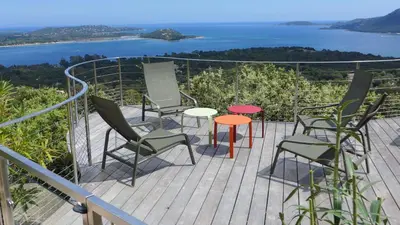 a deck with chairs and tables and a view of the ocean at Villa Panorama Porto-Vecchio in Porto-Vecchio