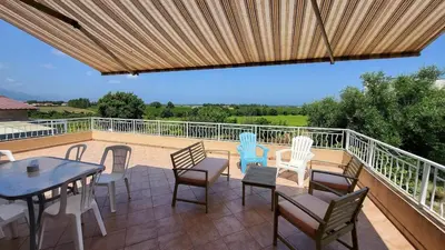 a patio with a table and chairs on a deck at Grand appartement Vescovato entre mer et montagne in Vescovato