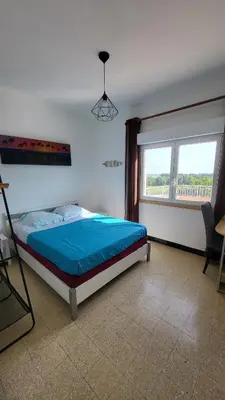 a bedroom with a bed and a large window at Grand appartement Vescovato entre mer et montagne in Vescovato