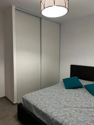a bedroom with a bed and a chandelier at Appartement T2 neuf résidence U Scalu in Santa-Lucia-di-Moriani