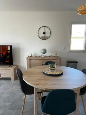 a dining room table with chairs and a clock on the wall at Appartement T2 neuf résidence U Scalu in Santa-Lucia-di-Moriani