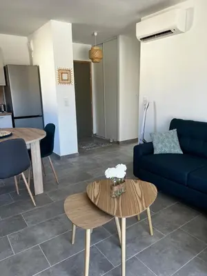 a living room with a blue couch and a table at Appartement T2 neuf résidence U Scalu in Santa-Lucia-di-Moriani