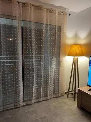 a curtain in a room with a lamp and a table at Appartement T2 neuf résidence U Scalu in Santa-Lucia-di-Moriani