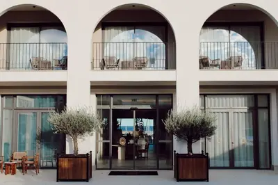 a white building with two windows and two potted plants at Hôtel & Spa Best Western Premier A Storia Solenzara in Sari Solenzara