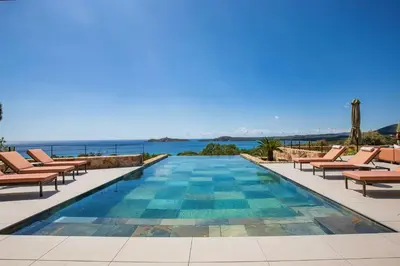 a pool with chairs and the ocean in the background at Villa Lucia Di Arinella in Pinarellu
