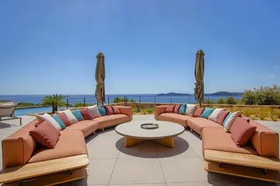 a patio with couches and a table and the ocean at Villa Lucia Di Arinella in Pinarellu