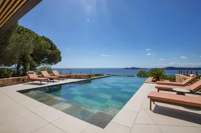 a swimming pool with chairs and the ocean in the background at Villa Lucia Di Arinella in Pinarellu