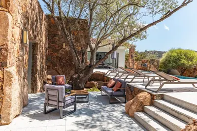 a patio with lounge chairs and a tree at Casa Carolina Di Palombaggia in Porto-Vecchio