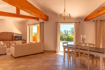 a dining room with a table and chairs and a couch at Villa Domaine de Pinarello in Pinarellu