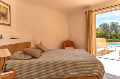 a bedroom with a bed with a view of a pool at Villa Domaine de Pinarello in Pinarellu