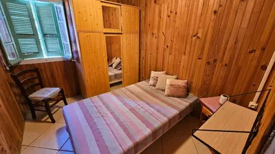 a small bedroom with a bed and a chair at CHALET BAVEDDA- Accès chemins de randonnée- Calme - Montagne in Quenza