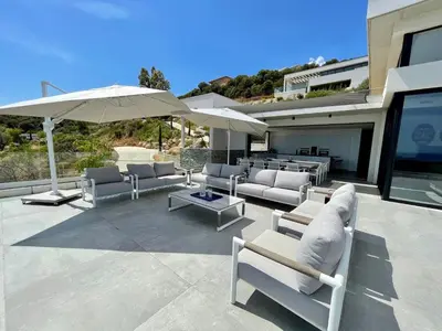 a patio with couches and an umbrella and tables at Villa contemporaine ORIZONTE - 15 pers - 400m2 vue mer in Zonza