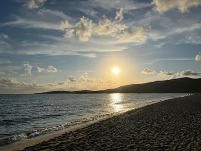 a beach with the sun setting over the water at Maison 30 mètres de la plage in Serra-di-Ferro