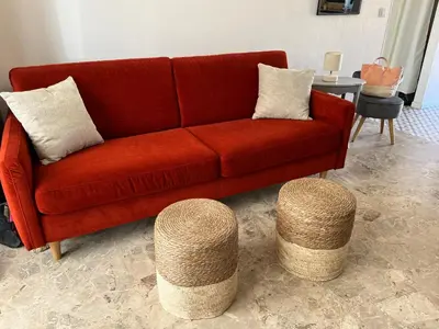 a red couch and two stools in a living room at Maison 30 mètres de la plage in Serra-di-Ferro