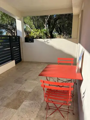 a red table and two red chairs on a patio at Maison 30 mètres de la plage in Serra-di-Ferro