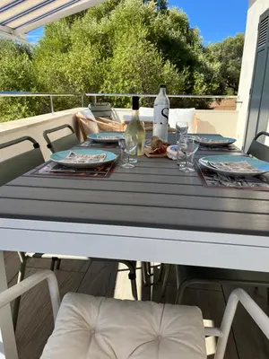 a table with glasses and wine bottles on a deck at Maison 30 mètres de la plage in Serra-di-Ferro