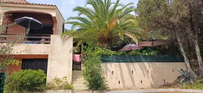 a house with two umbrellas on top of a fence at Duplex bord de mer avec jardin in Serra-di-Ferro