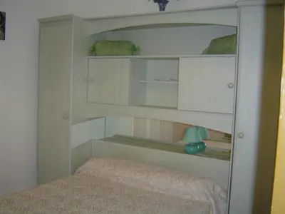 a bedroom with a bed and a mirror at chez Ange et Maryse à Olmeta di tuda in Olmeta-di-Tuda