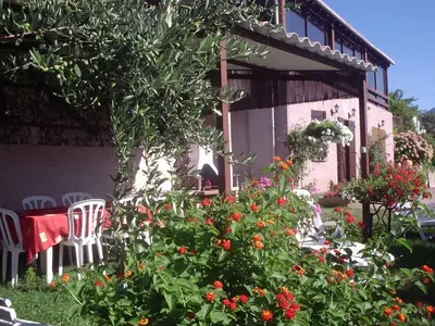 a table and chairs and flowers in front of a house at chez Ange et Maryse à Olmeta di tuda in Olmeta-di-Tuda