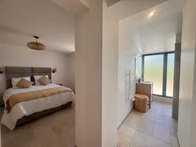 a bedroom with a bed and a large window at Superbe Villa Arià avec piscine chauffée in Calenzana