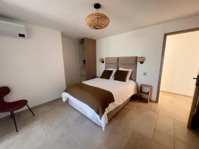 a bedroom with a bed and a chair at Superbe Villa Arià avec piscine chauffée in Calenzana