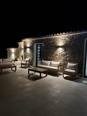 a room with couches and tables and a brick wall at Superbe Villa Arià avec piscine chauffée in Calenzana