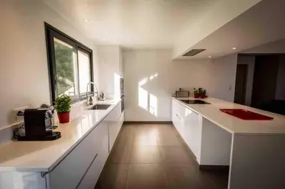 a large kitchen with white counters and a large window at La Prairie in Porto-Vecchio