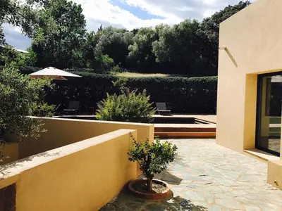 a house with a patio with a tree and an umbrella at La Prairie in Porto-Vecchio