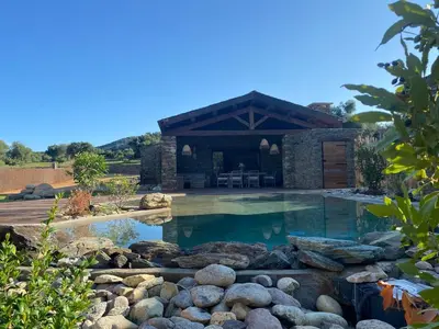 a swimming pool with a pavilion and rocks in a yard at U Casellu in Oletta