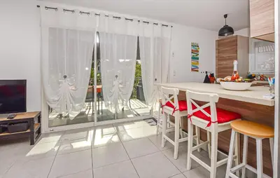 a kitchen with a table and chairs and a television at Villa Moderne Plage À Pieds in Prunete