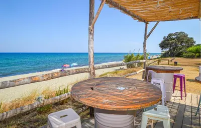 a table and chairs on the beach near the ocean at Villa Moderne Plage À Pieds in Prunete