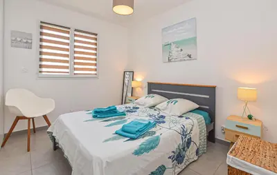 a bedroom with a bed with a chair and a window at Villa Moderne Plage À Pieds in Prunete