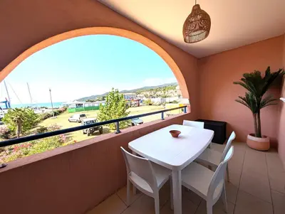 a balcony with a white table and chairs and a window at Apartment at Solenzara Marina in Sari Solenzara