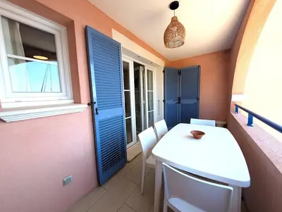a small room with blue shutters and a white table and chairs at Apartment at Solenzara Marina in Sari Solenzara