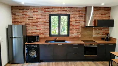a kitchen with a washer and a brick wall at Appartement neuf avec extérieur de plein pieds in Levie