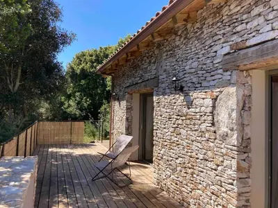 a stone house with a bench on a wooden deck at charmante bergerie in Bonifacio