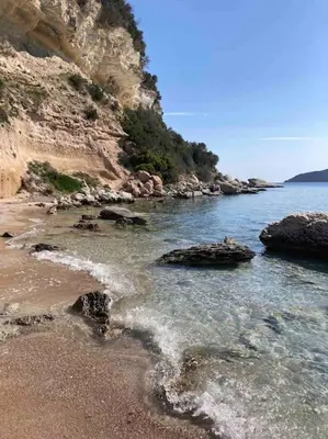 a beach with rocks and water and a mountain at charmante bergerie in Bonifacio