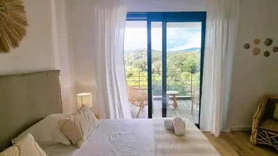 a bedroom with a bed and a view of a balcony at Villa Juca, 10 pers, piscine chauffée, 10 minutes plage in Cirendinu